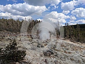 Plume of steam rising high from rocks at Yellowstone National Park
