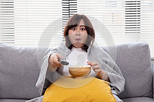 Plump Asian Woman with Shocking Face Watching Excited Television Show While Eating Popcorn on the Couch