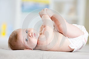 Plump baby lying down on a blanket and holding his feet