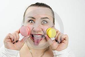 plump cheerful woman stuck out her tongue holds two macarons in her hands bake eyes laugh red lipstick white clothes