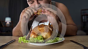 Plump male eating fatty fried chicken hungrily, high-calorie food and addiction