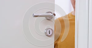 Plump man opens white door moving metal handle down macro