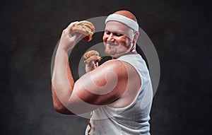 Plump men smiling with two hamburgers in his hands