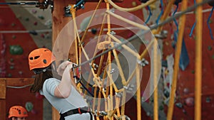 A plump overweight girl is engaged in extreme sports in a rope park indoors