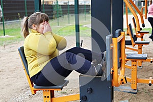 Plump sad girl closed her face with hands, motivation of healthy lifestyle, sports street simulators
