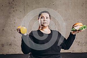 Plump woman chosing sport or junk food