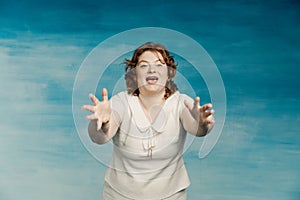 Plump woman screams something, bulging her eyes and waving arms on a blue background