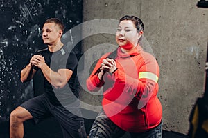 Plump woman with a sporty man doing exercises in the sport center