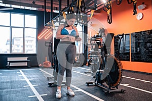 Plump woman wearing grey leggings and top measuring waistline