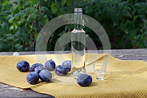 Plums brandy. Garden plums on an old wooden table with a tablecloth, copy space.