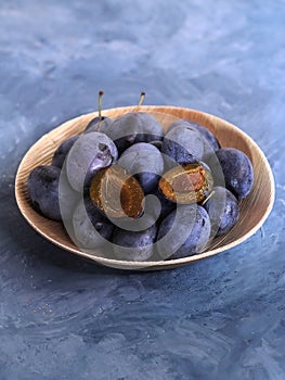 Plums in a bright bamboo bowl on a blue background