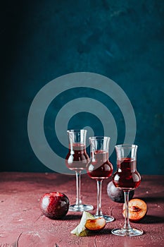 Plums strong alcoholic drink in grappas wineglass with dew. Hard liquor, slivovica, plum brandy or plum vodka with ripe plums on