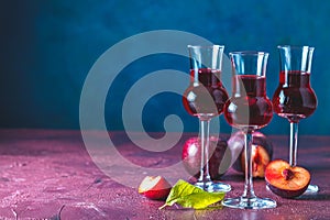 Plums strong alcoholic drink in grappas wineglass with dew. Hard liquor, slivovica, plum brandy or plum vodka with ripe plums on