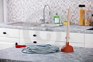 Plunger And Drainage Cable On Kitchen Worktop