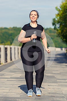 plus size active woman with a bottle of water during a morning jog