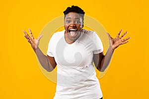 Plus-Size African Woman Screaming In Excitement Posing On Yellow Background