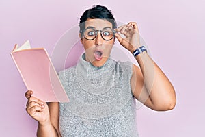 Plus size brunette woman reading a book wearing glasses afraid and shocked with surprise and amazed expression, fear and excited