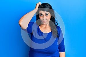 Plus size brunette woman wearing casual blue shirt confuse and wonder about question