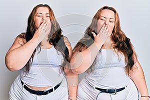 Plus size caucasian sisters woman wearing casual white clothes bored yawning tired covering mouth with hand