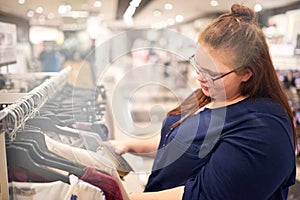 Plus size caucasian woman busy looking for clothing while shopping