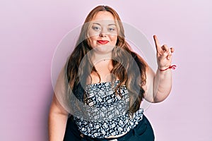 Plus size caucasian young woman wearing casual clothes smiling with an idea or question pointing finger up with happy face, number