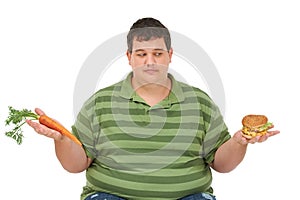Plus size, diet decision and man with a carrot and fast food choice thinking about balance. Male model, studio and white