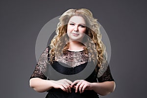 Plus size fashion model in black dress, fat woman on gray background