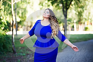 Plus size fashion model in blue dress outdoors, beauty woman with professional makeup and hairstyle, freedom concept