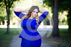 Plus size fashion model in blue dress outdoors, beauty woman with professional makeup and hairstyle, freedom concept