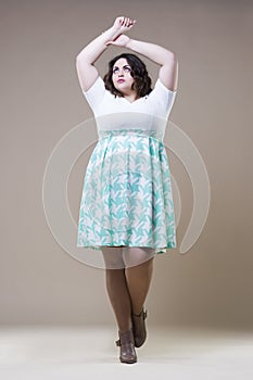 Plus size fashion model in casual clothes, fat woman on beige studio background, overweight female body