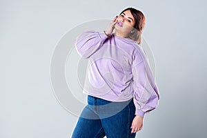 Plus size fashion model in casual clothes, fat woman on gray background