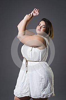 Plus size fashion model in casual clothes, fat woman on gray background, overweight female body