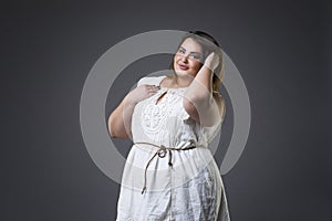 Plus size fashion model in casual clothes, fat woman on gray background, overweight female body