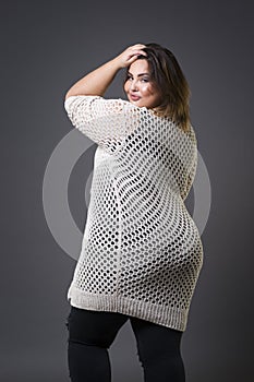 Plus size fashion model in casual clothes, fat woman on gray background, overweight female body