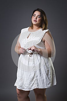 Plus size fashion model in casual clothes, fat woman on gray background, overweight female body
