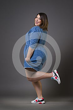 Plus size fashion model in casual clothes, fat woman on gray background, overweight female body