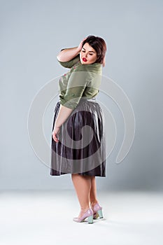 Plus size fashion model in casual clothes, fat woman on gray studio background