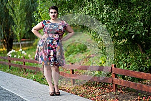 Plus size fashion model in floral dress outdoors, beautiful fat woman with big breasts in nature