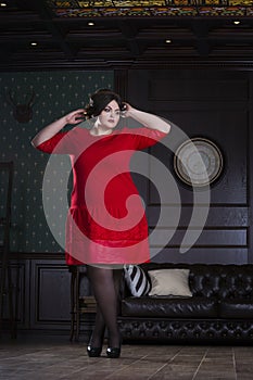 Plus size fashion model in red evening dress, fat woman on luxury interior, overweight female body, full length portrait
