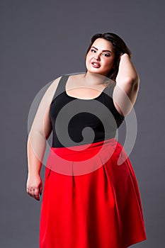 Plus size fashion model in red skirt, fat woman on gray background
