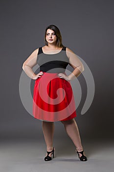 Plus size fashion model in red skirt, fat woman on gray background, overweight female body