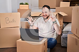 Plus size hispanic man with beard moving to a new home doing video call smiling with an idea or question pointing finger with