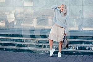 Plus size model with blond curly hair in knitted sweater outdoor