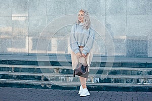 Plus size model with blond curly hair in knitted sweater outdoor