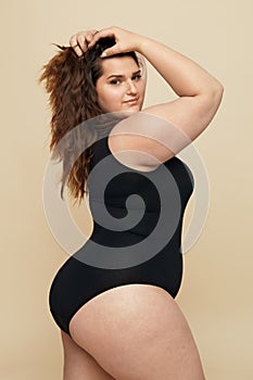 Plus Size Model. Fat Woman In Black Bodysuit Portrait. Brunette Touching Hair And Looking At Camera.