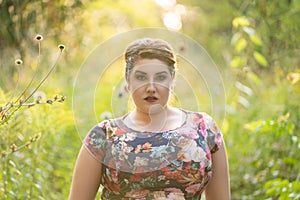 Plus size model in floral dress outdoors, beautiful fat woman with big breasts in nature