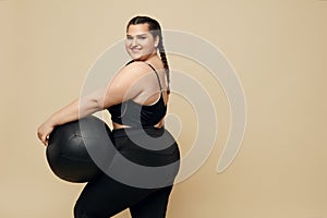 Plus Size Model. Full-Figured Woman In Black Sportswear Portrait. Brunette Holding Fitness Ball.