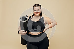 Plus Size Model. Full-Figured Woman In Black Sportswear Portrait. Brunette Holding Fitness Mat.