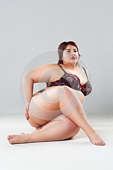 Plus size model in lingerie, fat sexy woman in underwear on gray background, body positive concept