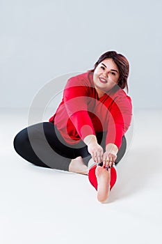 Plus size model in sportswear, fat woman doing workout on gray background, healthy lifestyle concept